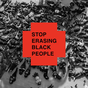 a red plus or cross with the words "stop erasing black people" written on it, with die-in black lives matter protesters in the background